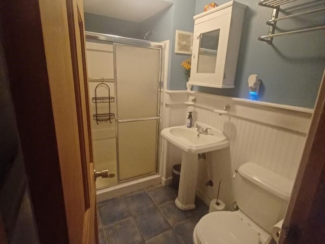 bathroom with tile patterned floors, toilet, and a shower with shower door