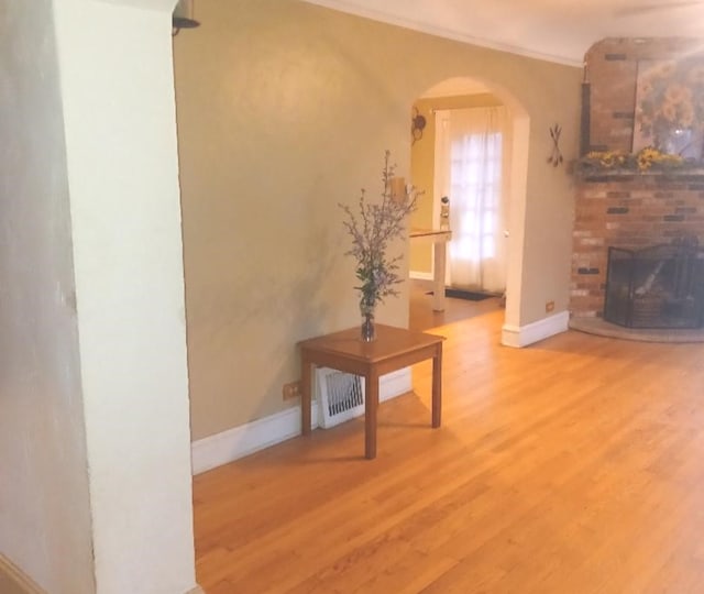 interior space featuring a fireplace, ornamental molding, and hardwood / wood-style flooring