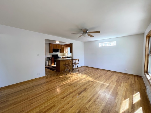 unfurnished living room featuring ceiling fan and light wood-type flooring