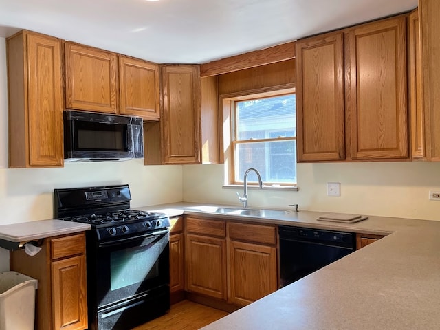 kitchen with black appliances, sink, and light hardwood / wood-style flooring