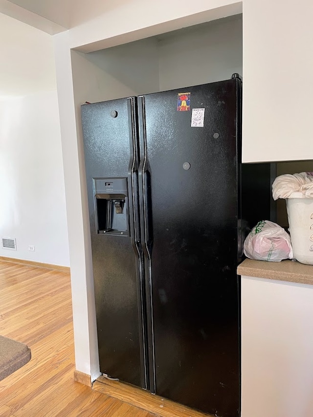 kitchen with light wood-type flooring and black fridge