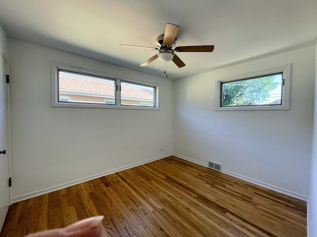 empty room featuring ceiling fan, hardwood / wood-style flooring, and a healthy amount of sunlight