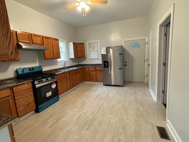 kitchen with light wood-type flooring, stainless steel refrigerator with ice dispenser, sink, and black gas range