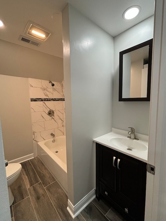 full bathroom with tiled shower / bath, vanity, and toilet