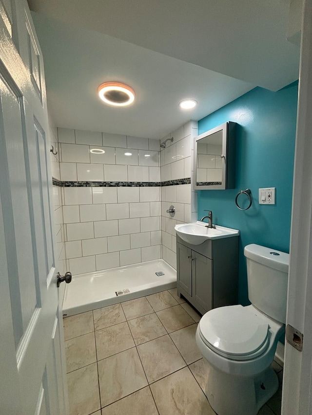 bathroom featuring tiled shower, vanity, toilet, and tile patterned flooring