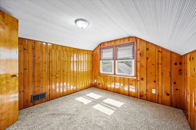 additional living space featuring wooden walls, lofted ceiling, and carpet