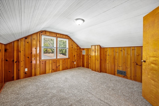 additional living space with lofted ceiling, wood walls, and carpet floors