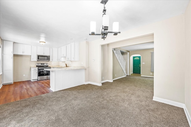 kitchen with white cabinets, sink, kitchen peninsula, stainless steel appliances, and dark colored carpet