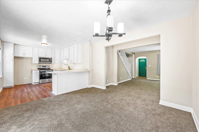 920 S 5th St, Watseka, IL 60970 - kitchen featuring white cabinetry, light countertops, stainless steel appliances, arched walkways, and carpet