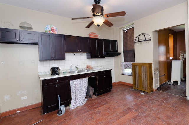 kitchen with light stone counters, dark hardwood / wood-style floors, sink, decorative backsplash, and ceiling fan