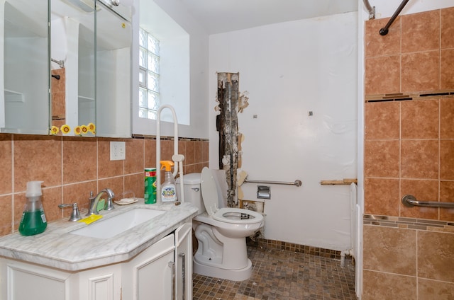 bathroom featuring a tile shower, tile walls, tile patterned floors, vanity, and toilet