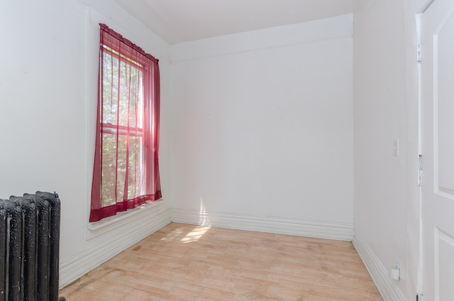 empty room with radiator heating unit and light hardwood / wood-style flooring