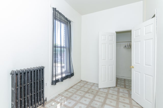 unfurnished bedroom featuring a closet and radiator heating unit