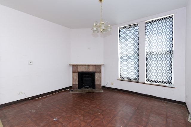 unfurnished living room featuring a tile fireplace, a chandelier, and dark parquet flooring