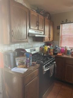 kitchen featuring black range oven, tile patterned flooring, and backsplash