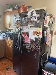 kitchen featuring tile patterned floors and black refrigerator with ice dispenser