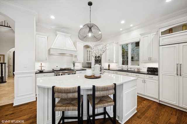 kitchen featuring custom range hood, dark hardwood / wood-style floors, a center island, and white cabinetry