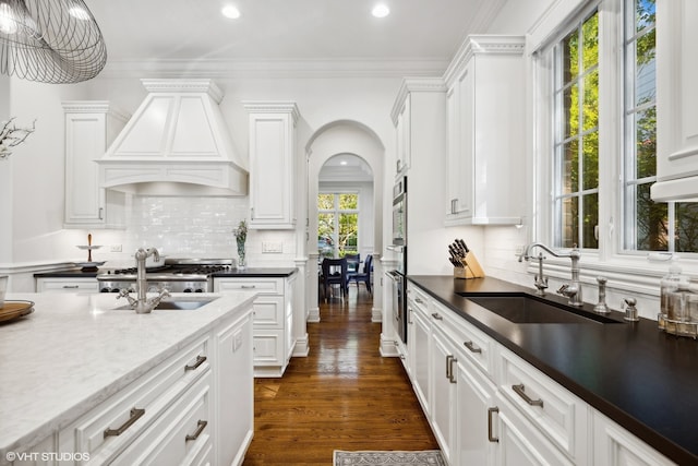 kitchen with white cabinets, ornamental molding, sink, dark hardwood / wood-style floors, and custom range hood