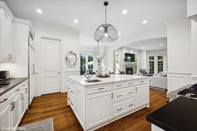 kitchen featuring white cabinets, a center island with sink, plenty of natural light, and dark wood-type flooring