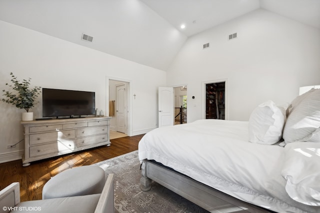 bedroom with dark wood-type flooring, a spacious closet, a closet, high vaulted ceiling, and connected bathroom