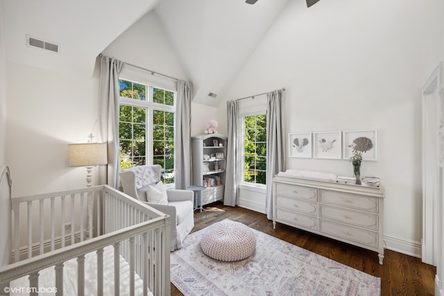 bedroom with dark hardwood / wood-style floors, a crib, high vaulted ceiling, and multiple windows