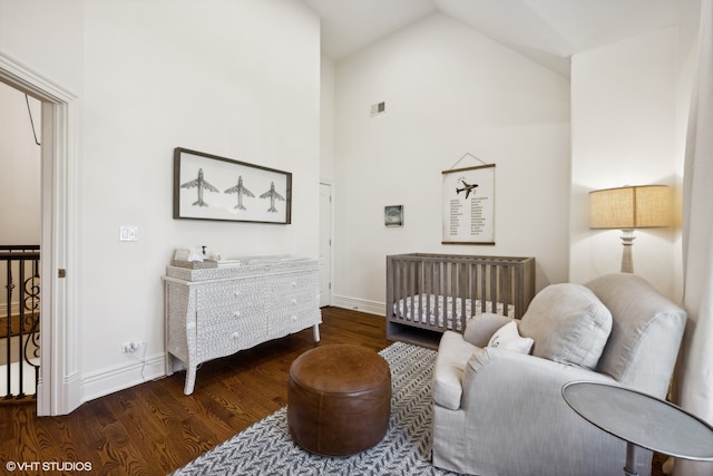 bedroom featuring high vaulted ceiling, a crib, and dark hardwood / wood-style flooring