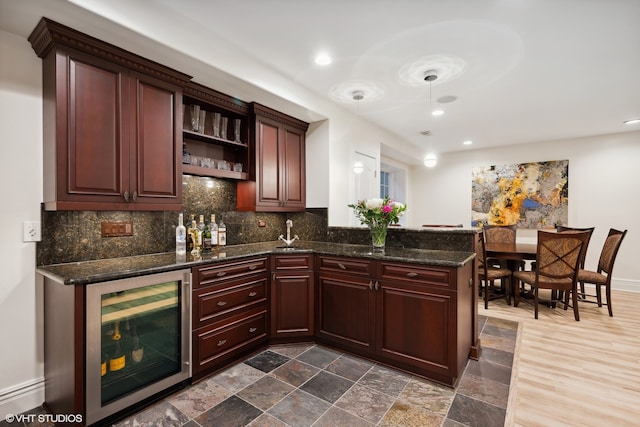 kitchen with tasteful backsplash, hanging light fixtures, wine cooler, and dark stone countertops