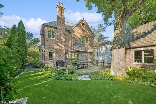 rear view of house featuring a lawn and a patio