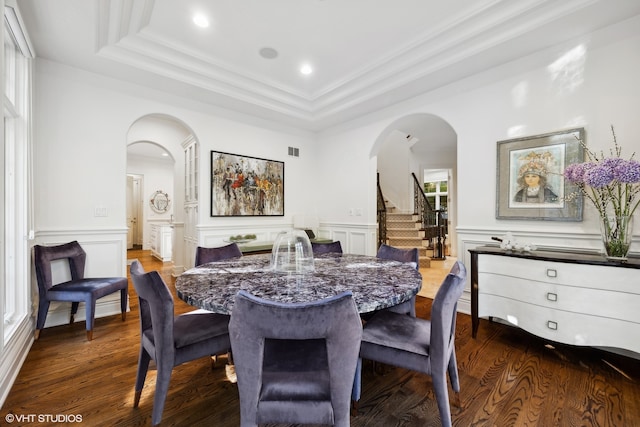 dining area with a raised ceiling, wood-type flooring, crown molding, and a healthy amount of sunlight