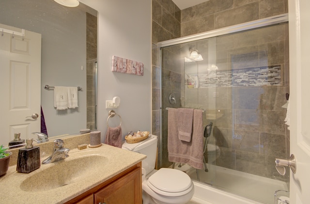 bathroom featuring vanity, toilet, and a shower with door