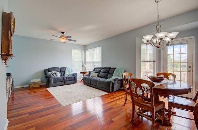 dining space with ceiling fan with notable chandelier and dark wood-type flooring