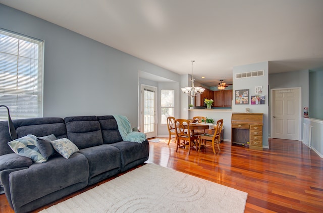 living room with ceiling fan with notable chandelier and dark wood-type flooring