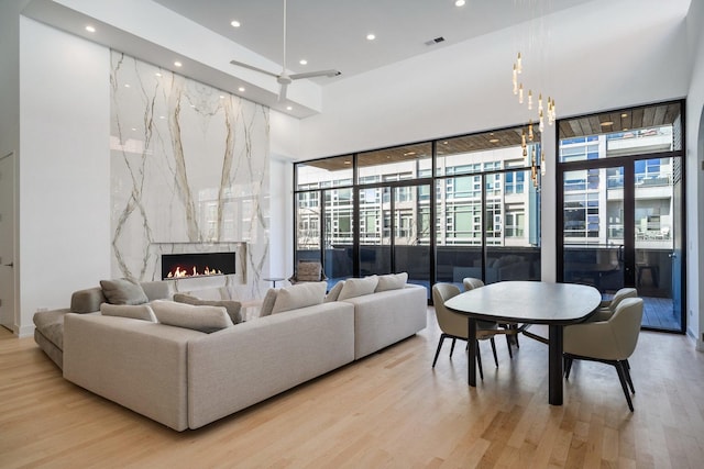 living area featuring recessed lighting, visible vents, wood finished floors, and a high end fireplace