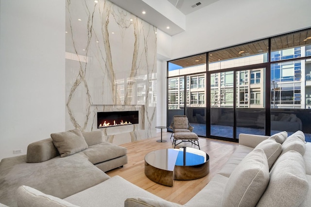 living room with a high end fireplace, recessed lighting, a high ceiling, and wood finished floors