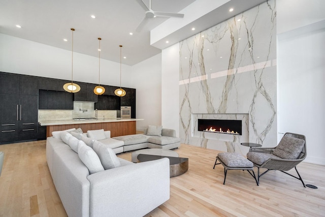 living area featuring ceiling fan, a premium fireplace, light wood-type flooring, and recessed lighting