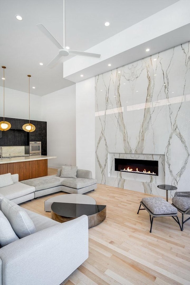 sunken living room featuring a premium fireplace, wood finished floors, and recessed lighting