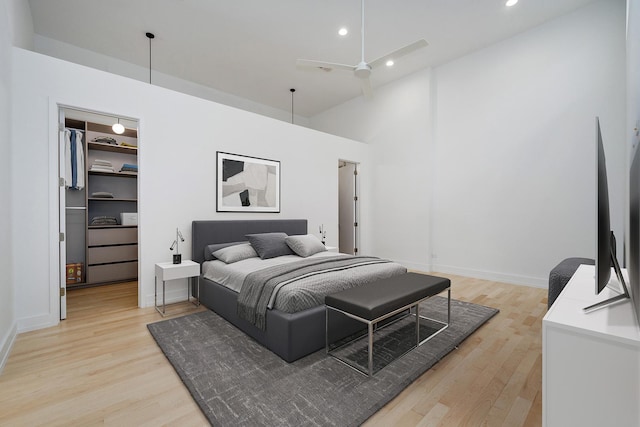 bedroom featuring light wood finished floors, a walk in closet, a high ceiling, and recessed lighting