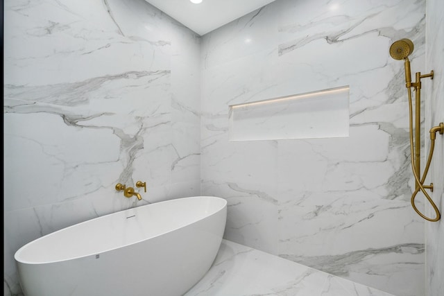 bathroom with a freestanding bath, stone wall, and a marble finish shower