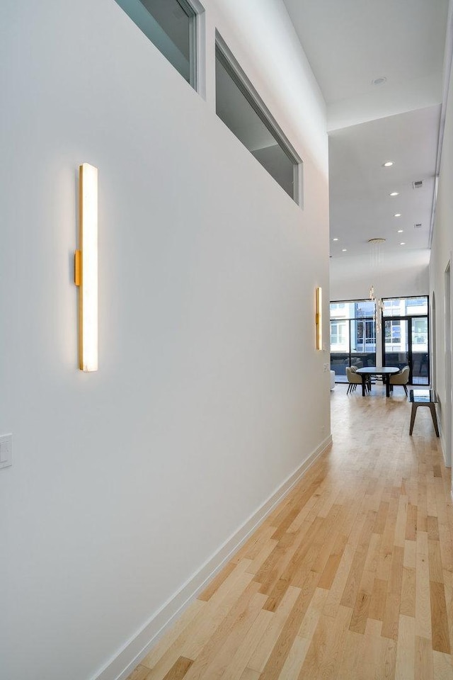 corridor with light wood-style floors, recessed lighting, and baseboards