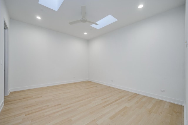 unfurnished room featuring a skylight, light wood-style flooring, and recessed lighting