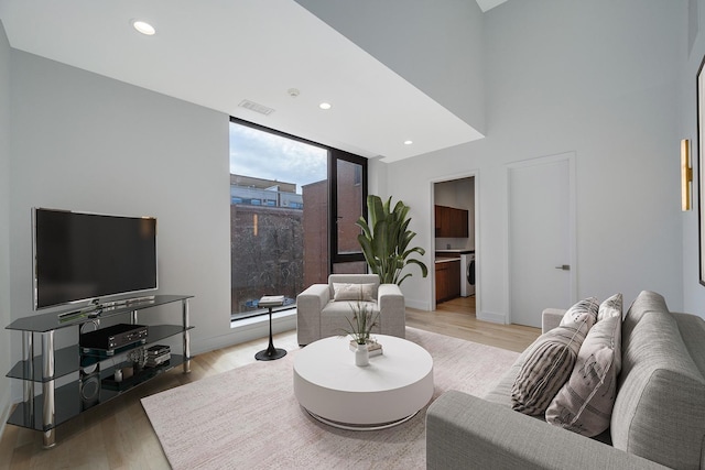 living room featuring visible vents, baseboards, light wood-style flooring, washer / clothes dryer, and recessed lighting