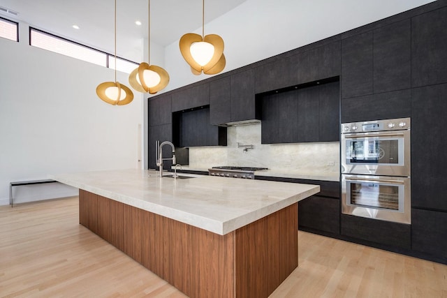 kitchen with stainless steel appliances, dark cabinetry, a sink, and light countertops