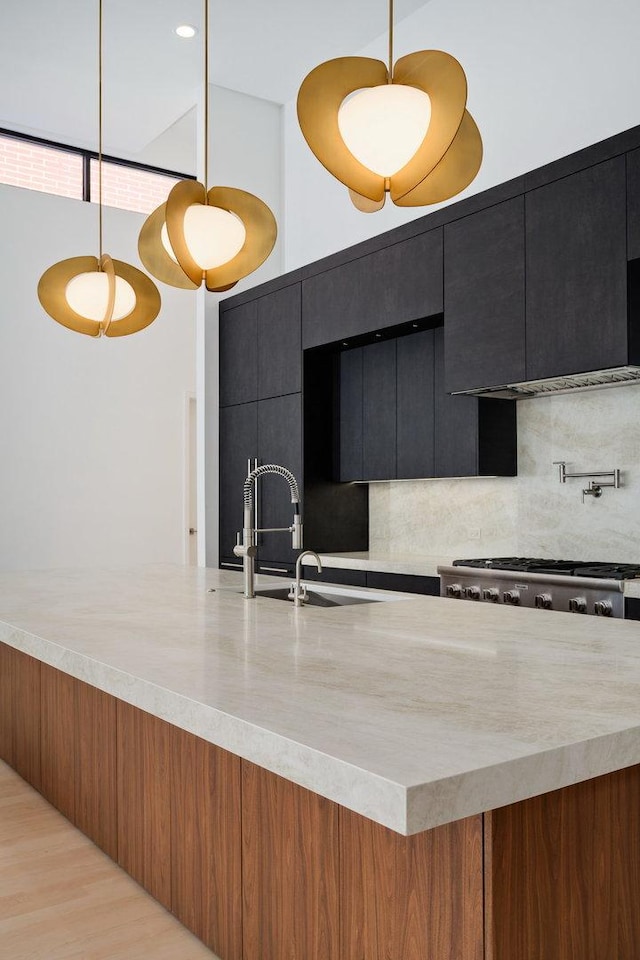 kitchen with a sink, dark cabinetry, decorative backsplash, modern cabinets, and decorative light fixtures