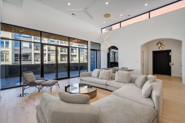 living area featuring light wood-style flooring, visible vents, arched walkways, and recessed lighting