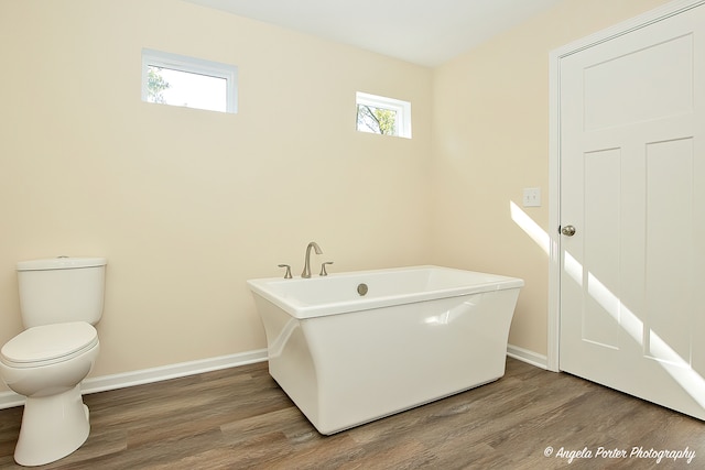 bathroom featuring wood-type flooring, a bathing tub, and toilet