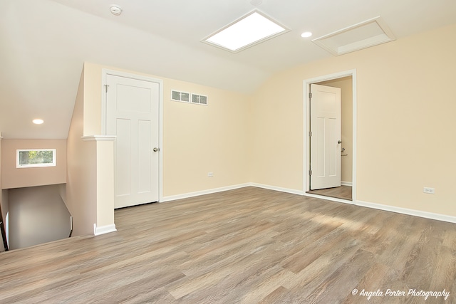 empty room featuring vaulted ceiling and light hardwood / wood-style flooring