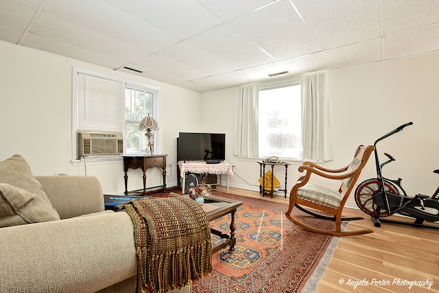 living room with cooling unit, a drop ceiling, and light hardwood / wood-style floors