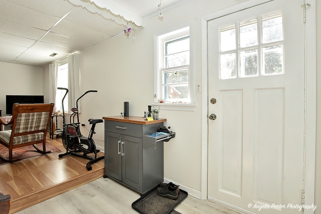 interior space featuring a drop ceiling and light hardwood / wood-style flooring