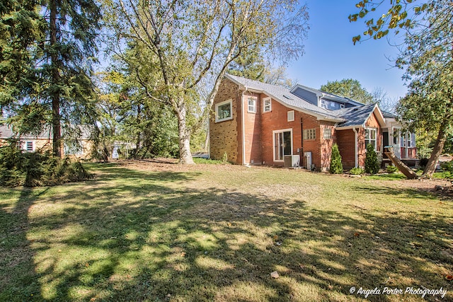 view of side of property featuring a yard and central AC