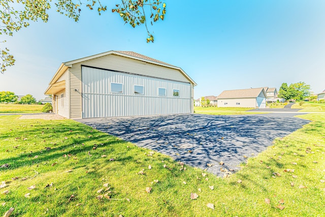 exterior space featuring a garage, a lawn, and an outbuilding